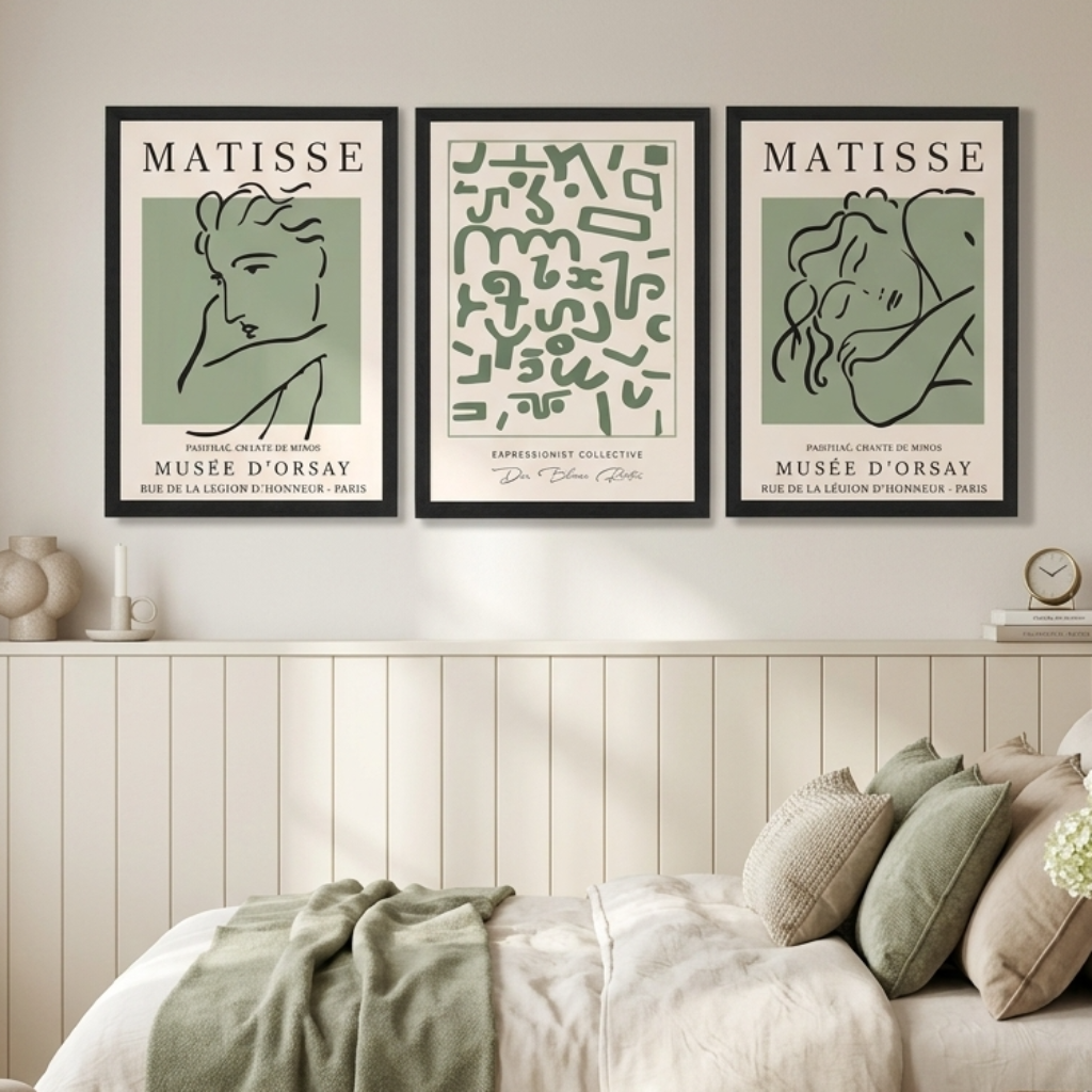 Three framed Matisse art prints in black frames hang on a beige wall above a bed in a styled bedroom. 