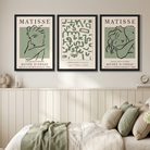 Three framed Matisse art prints in black frames hang on a beige wall above a bed in a styled bedroom. 