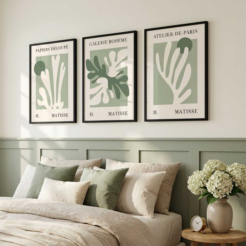 Three framed Matisse-inspired botanical art prints in black frames hang above a bed in a styled bedroom. The prints feature abstract coral or leaf-like shapes in muted green and off-white on pale sage backgrounds, with French text at the top of each print.